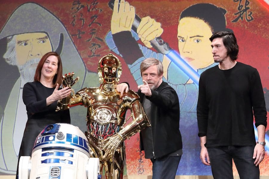 Kathleen Kennedy and Mark Hamill joking around while Adam Driver stands intensely. 