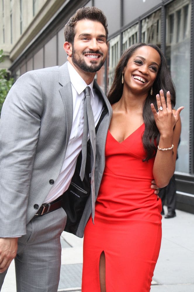 Rachel Lindsay and Bryan Abasolo posing in the street with Rachel’s engagement ring clearly displayed. 