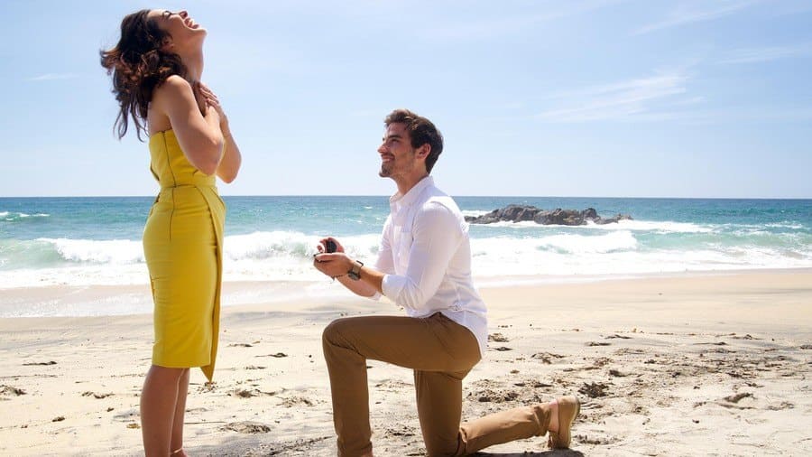 Jared down on one knee proposing to Ashley on the beach in Mexico. 