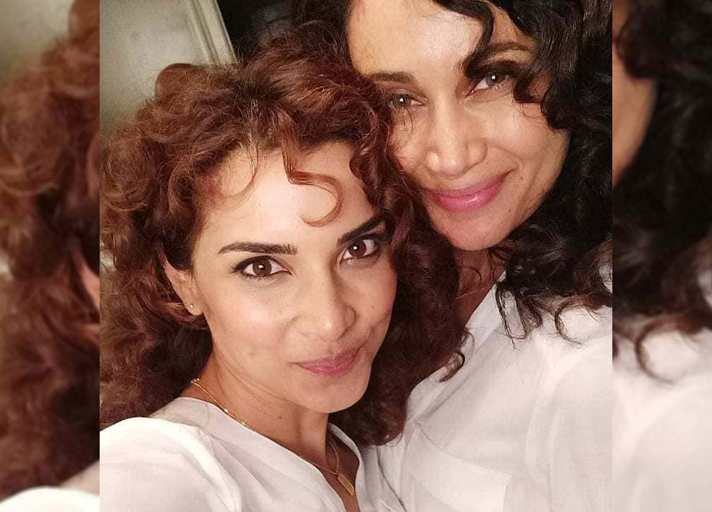 Amber Rose Revah and Aja Frary both with curled hair and white button-down shirts.