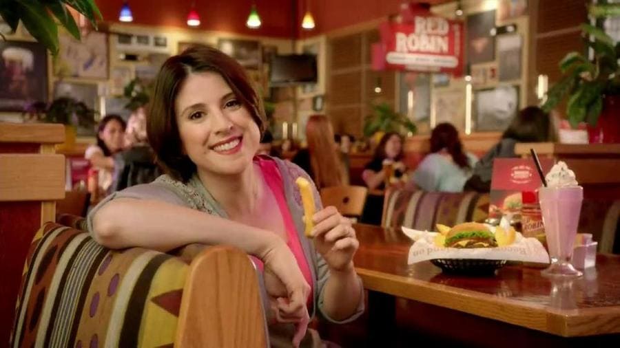 Melanie Paxson in a booth at Red Robin holding a French fry.