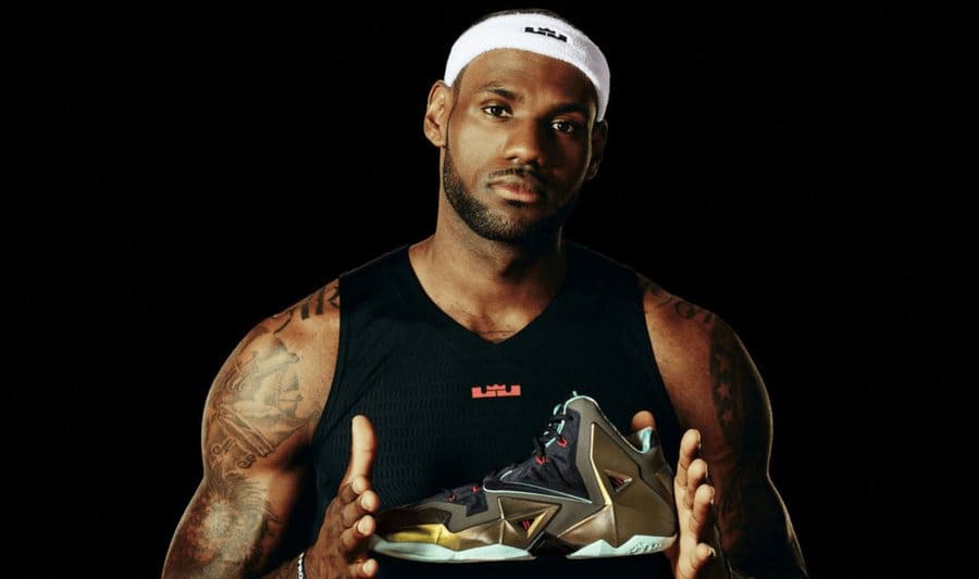 Lebron James holding up his gold black and red accented sneaker.