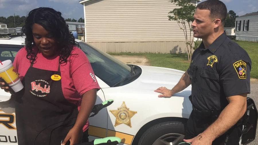 Sgt. Scott Bass talking to Jaylesya Corbett next to a cop car.