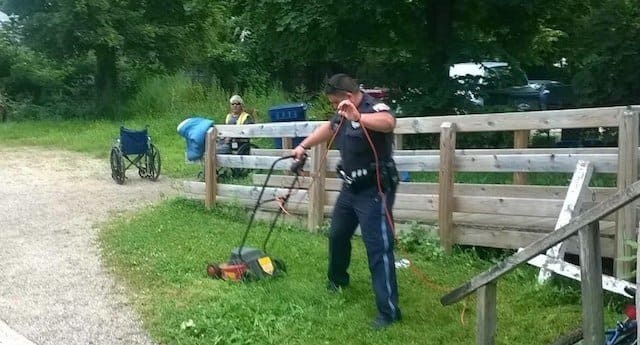 Cop mowing the lawn for a man in a wheelchair
