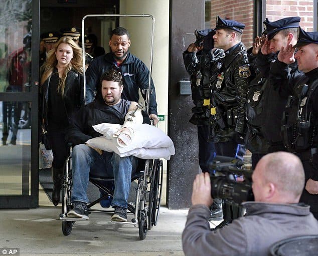 Officer Hartnett being wheeled out of the hospital in a wheelchair