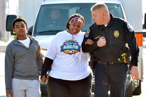 Cop walking arm in arm with the woman and her son.