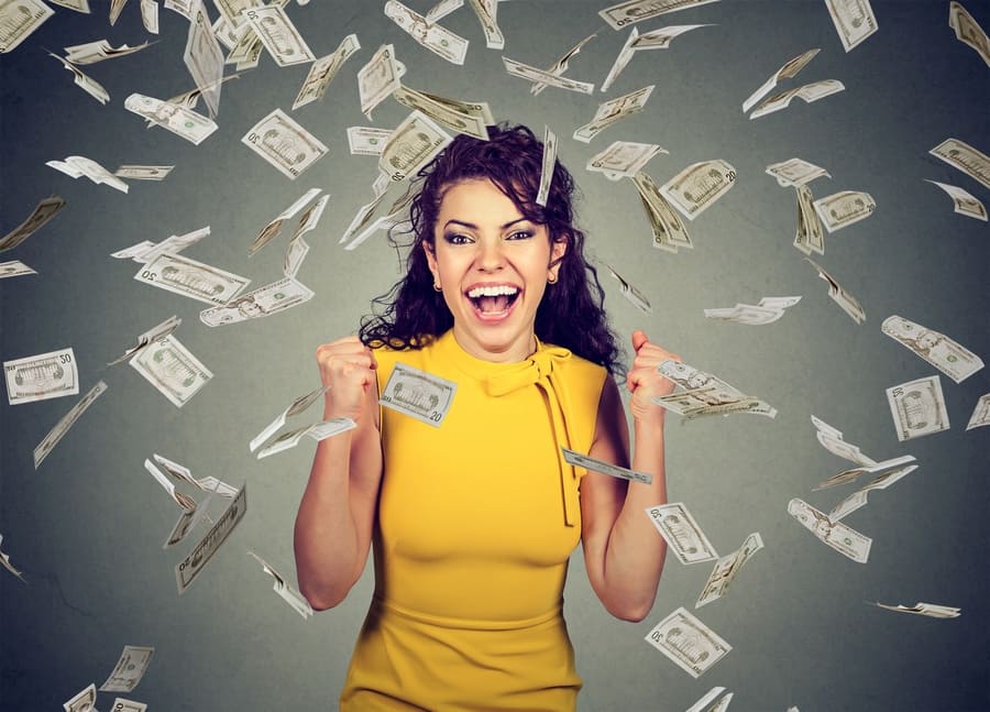 Portrait of a happy woman celebrating success under money falling down like rain.