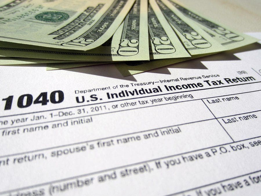 Photograph of a 1040 U.S. Individual Income Tax Return form along with five $20 bills.