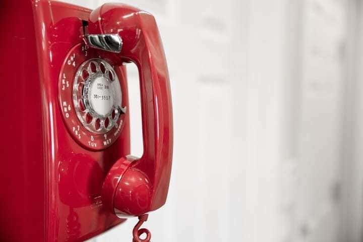 Photograph of a vintage red telephone with a turn dial.