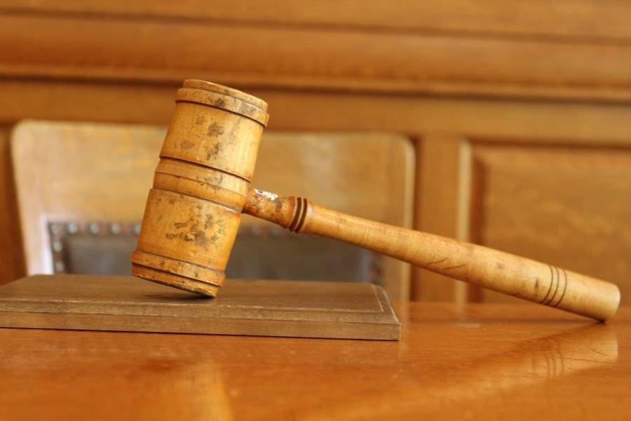 Photograph of a used light wooden gavel sitting on a judge's desk.