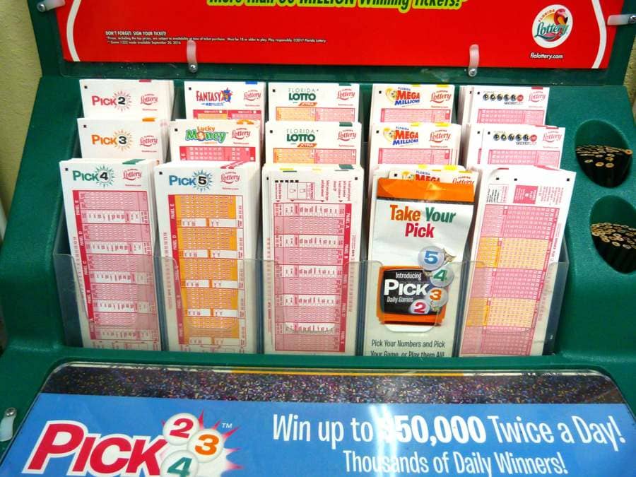 Photograph of a variety of lottery tickets with small black pencils on the side to fill out the tickets with.