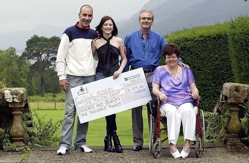 Photograph of Callie Rogers with her significant other and parents in front of a green lawn with trees and bushes.