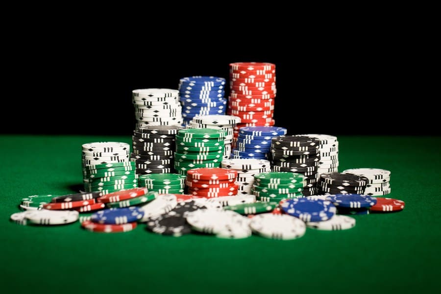 A close up photograph of casino chips on a green table surface.