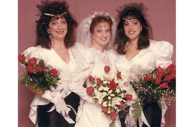 A Bride with her bridesmaids holding red roses