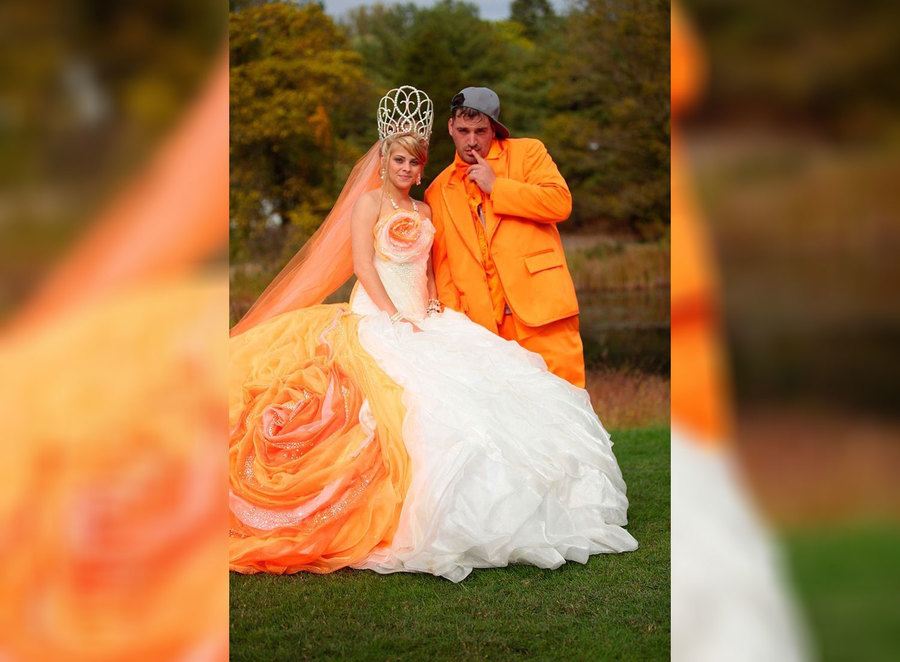 A bride with orange in her dress and a groom wearing an orange suit