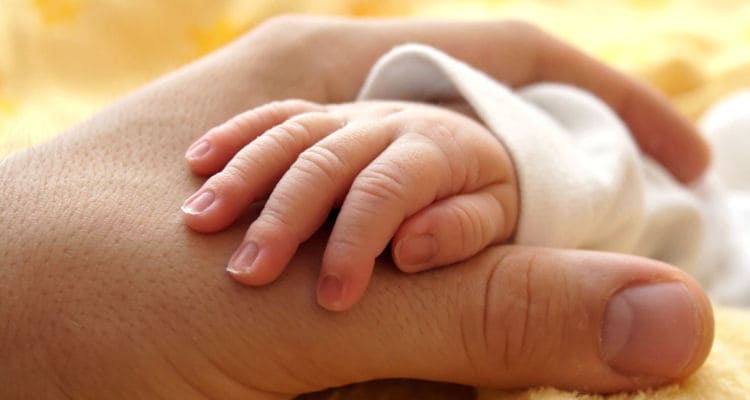 A baby’s hand holding his mother's hand. 