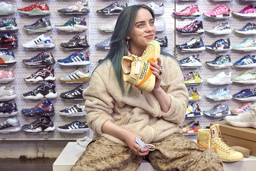 Billie Eilish is holding one of the pair of sneakers that she purchased during the YouTube segment.
