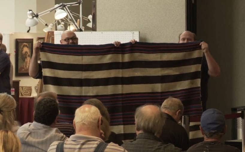 A photograph of employees holding up the blanket at the auction 
