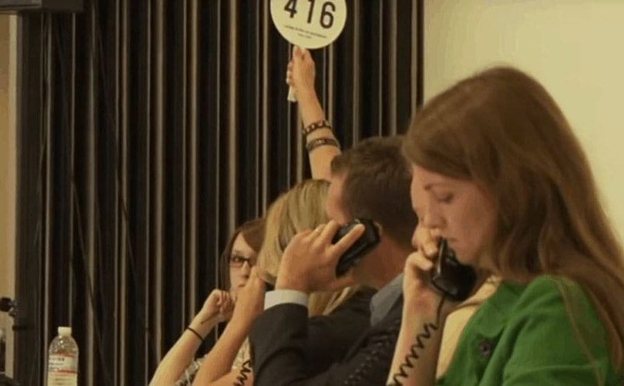 Auctioneers holding a paddle and on the phone 