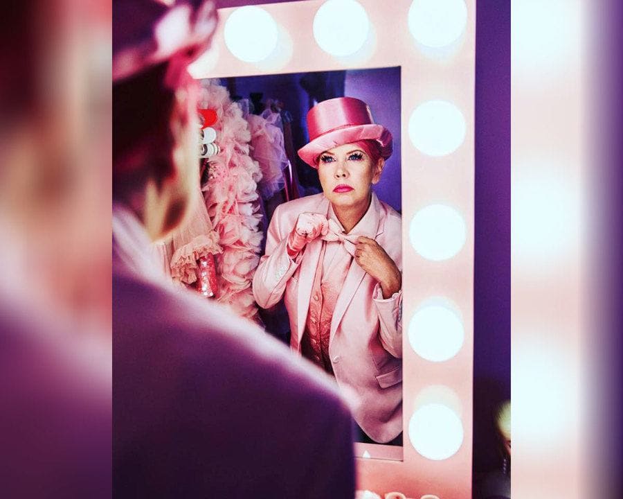 Kitten Kay Sera is adjusting a pink bowtie in the mirror.