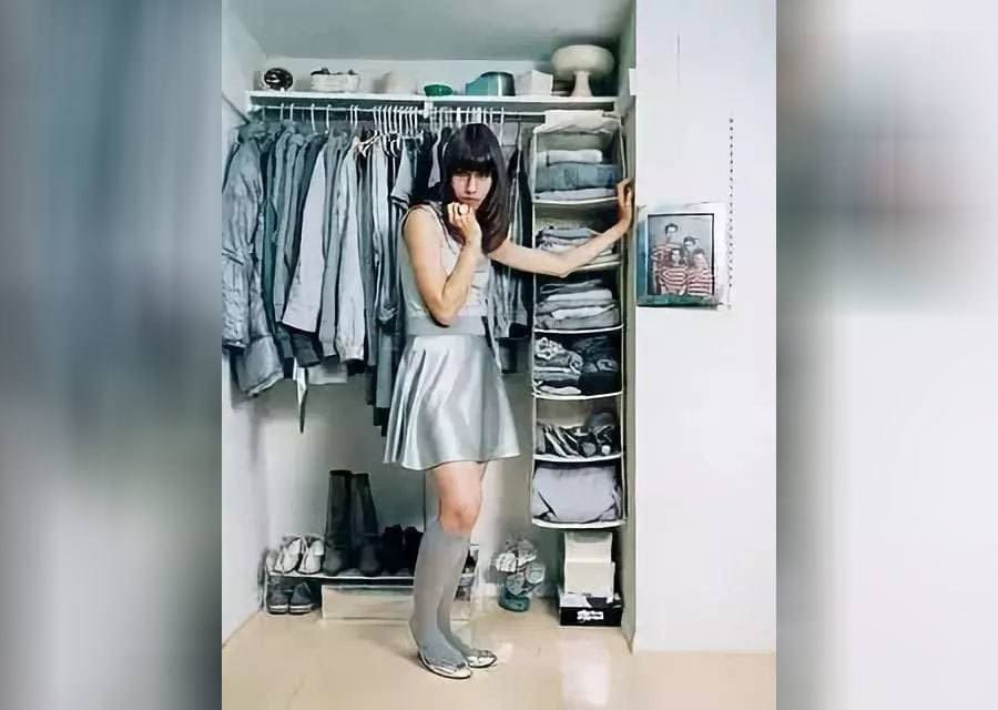 Rebecca Turbow is wearing all gray and silver standing in her closet