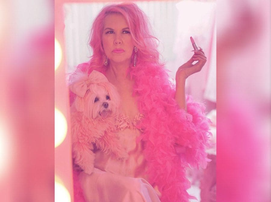 Kitten Kay Sera in front of a mirror holding her pink dog 