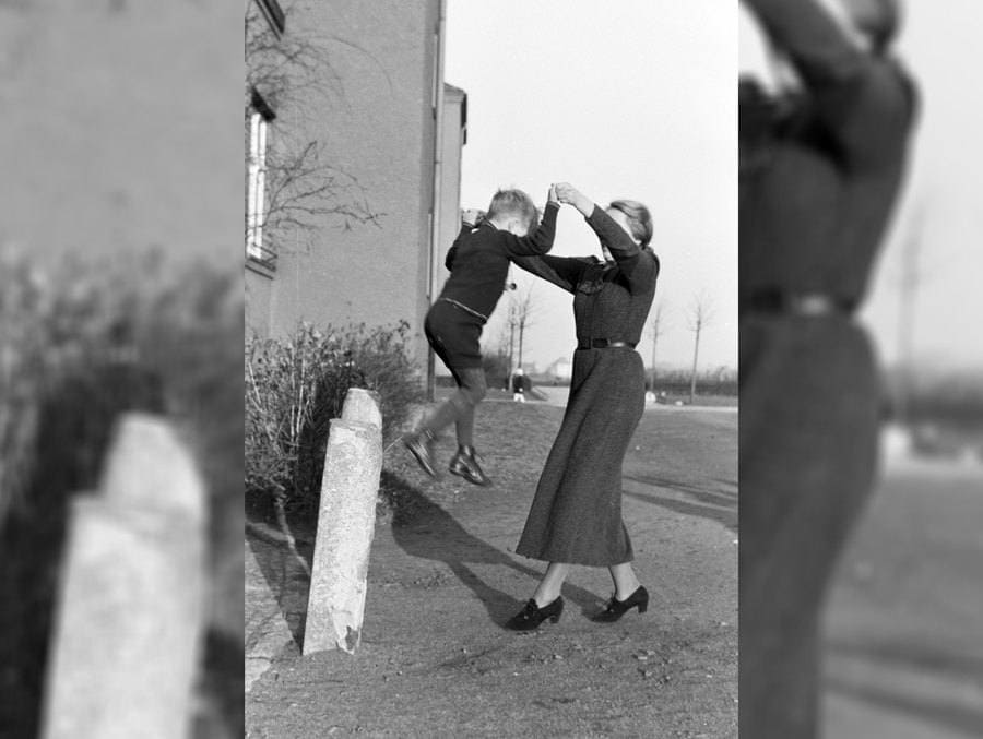 A mother and son playing at the side of an apartment 