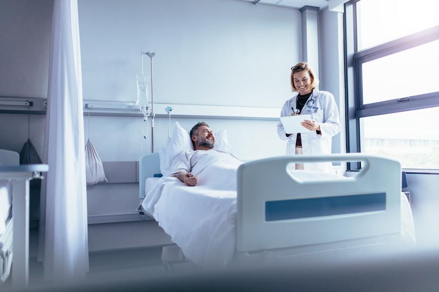 Female doctor talking to a male patient in a hospital bed