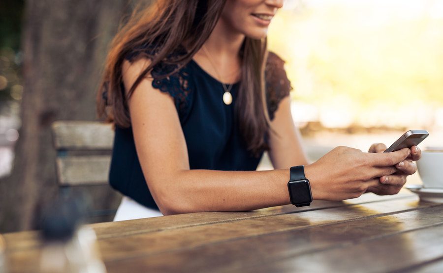 A woman on her phone with coffee next to her on the table