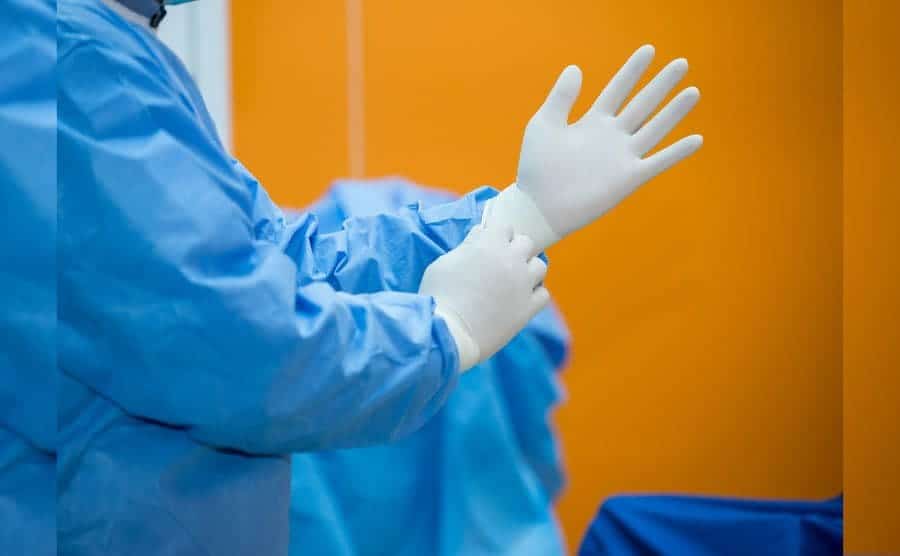 A surgeon putting on disposable surgical gown and gloves before going into the theater