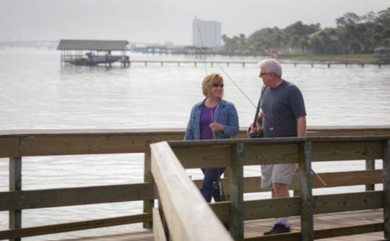 Kay and Marty walking along the shore with fishing rods