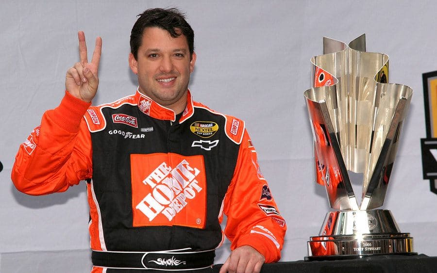 Tony Stewart standing next to the Nascar Trophy