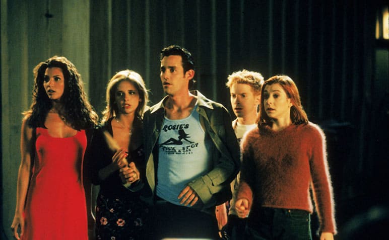 Charisma Carpenter, Sarah Michelle Gellar, Nicholas Brendon, Seth Green, and Alyson Hannigan standing defensively with Gellar holding a stake