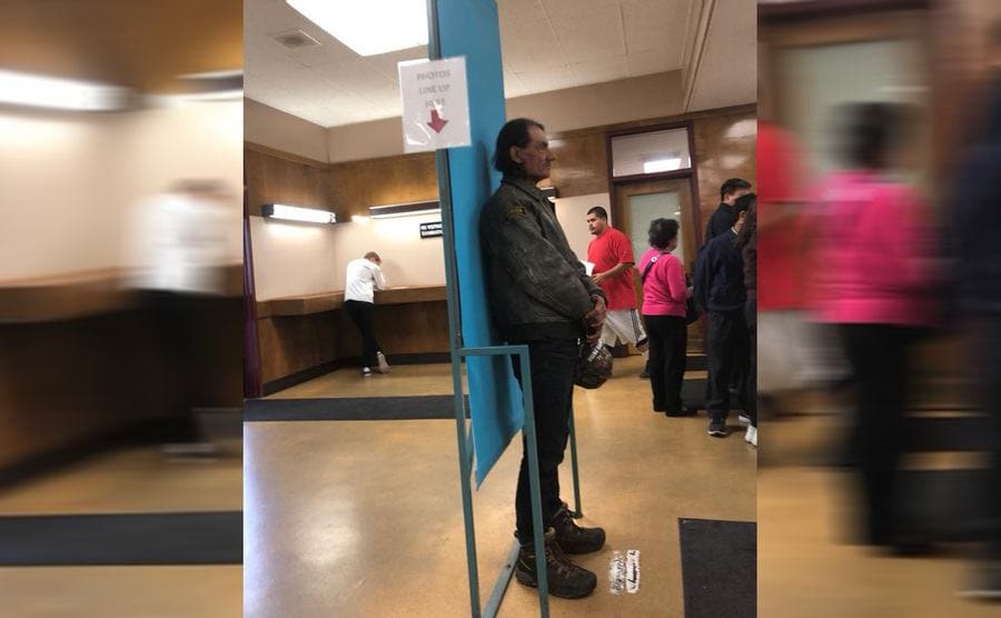 Mick standing in the DMV getting his photograph taken