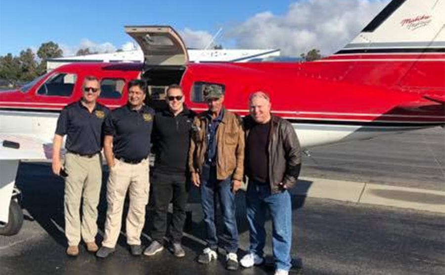 Mick with the deputy and others standing in front of a plane