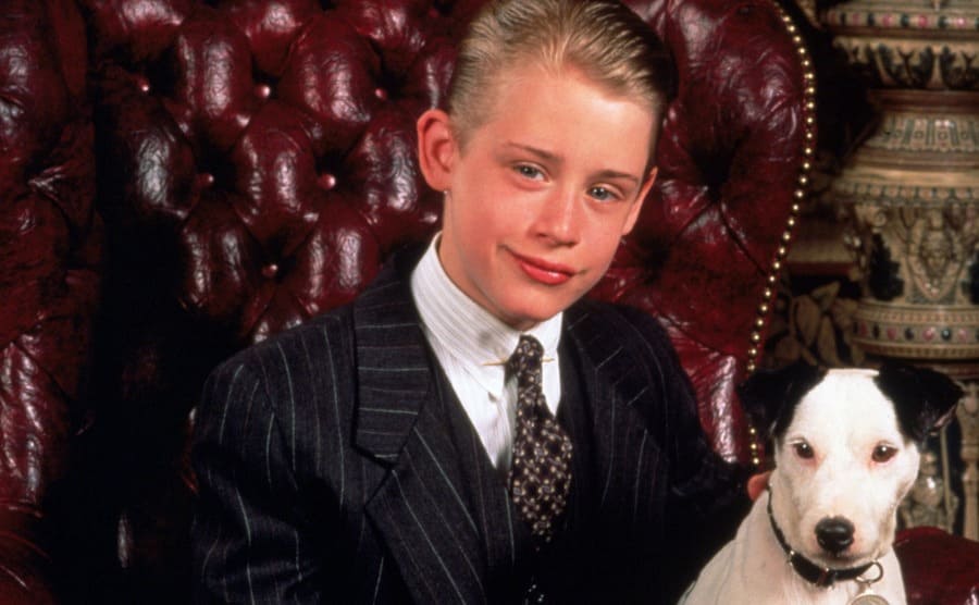 Macaulay Culkin and a dog sitting on a red leather chair