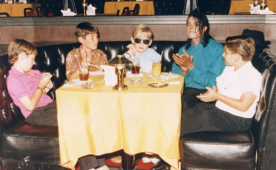 Macaulay Culkin and Michael Jackson with other boys drinking in a booth in 1991