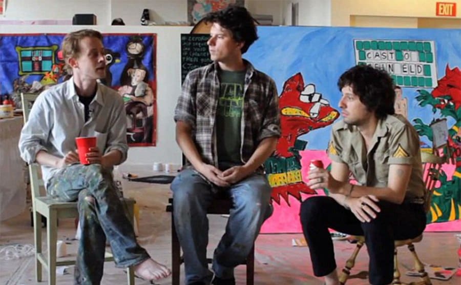 Macaulay Culkin, Adam Green, and Toby sitting with artwork around them