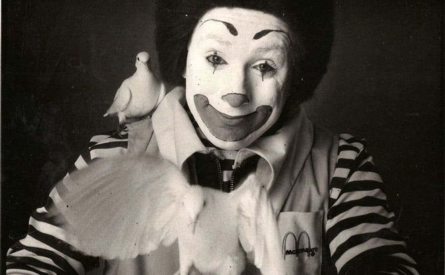Geoffrey Giuliano as Ronald McDonald with one dove on his shoulder and one flying out of the palm of his hand