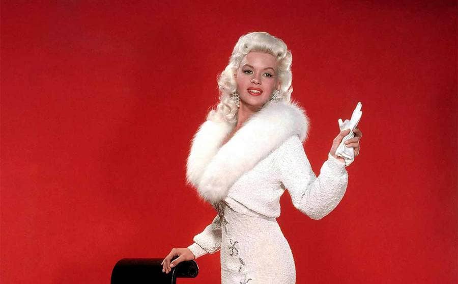 Jayne Mansfield posing in a white dress with a fur collar