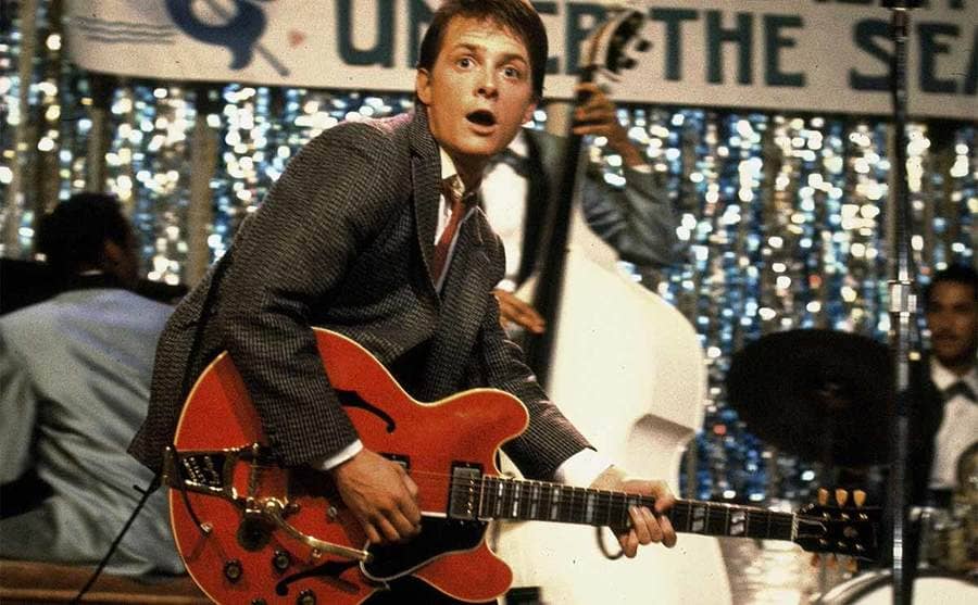 Michael J Fox playing the guitar on stage in a scene from Back to the Future