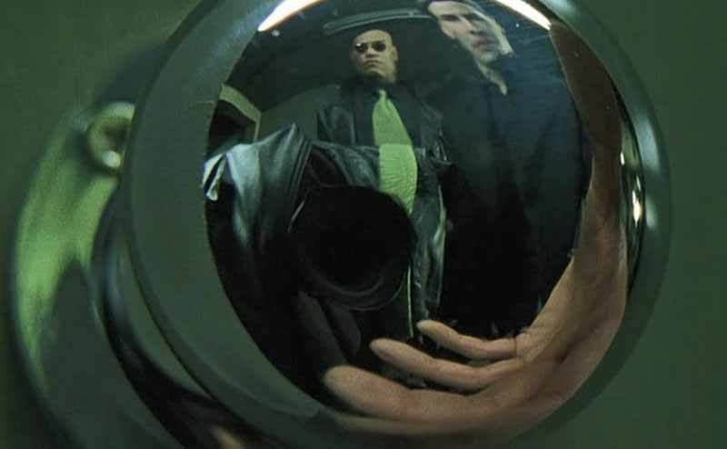 A scene from The Matrix of people’s reflection in a doorknob along with the reflection of the video camera