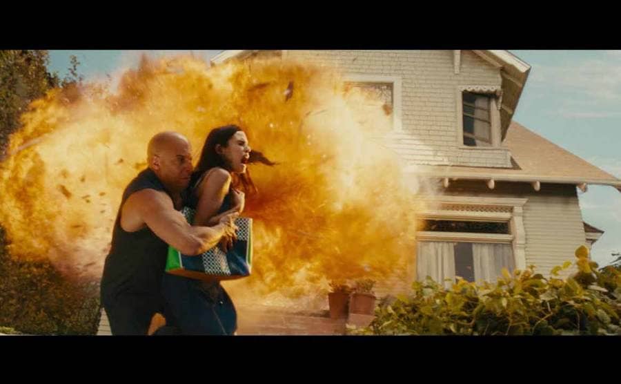 Vin Diesel pushing Jordana Brewster out of the way while a house explodes behind them