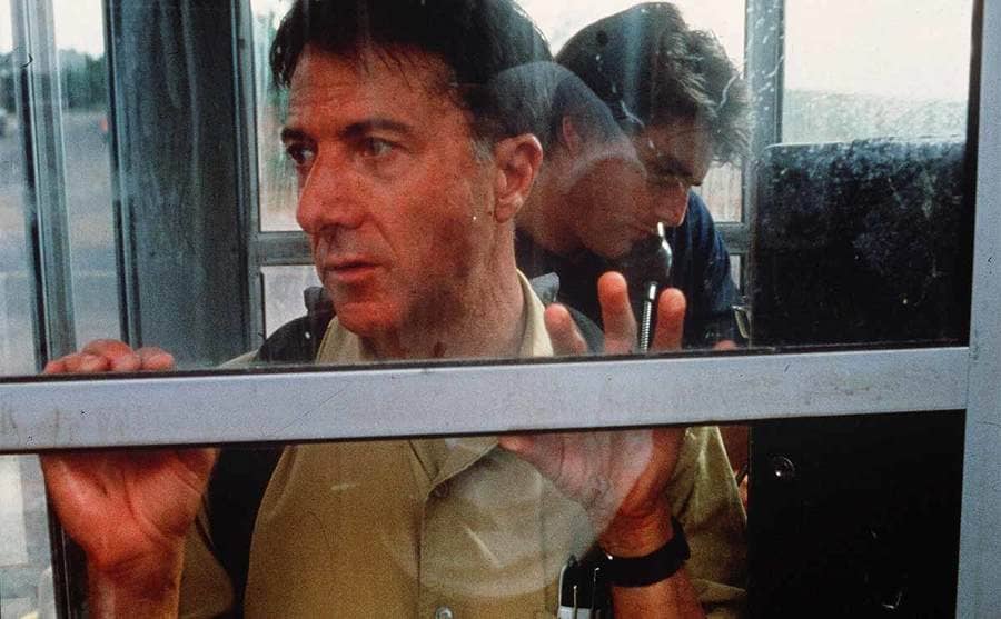 Dustin Hoffman looking out of the phone booth while Tom Cruise makes a call in the film Rain Man