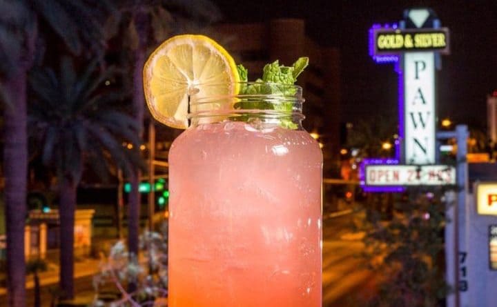 A cocktail in a mason jar in front of a view of the Gold and Silver pawnshop