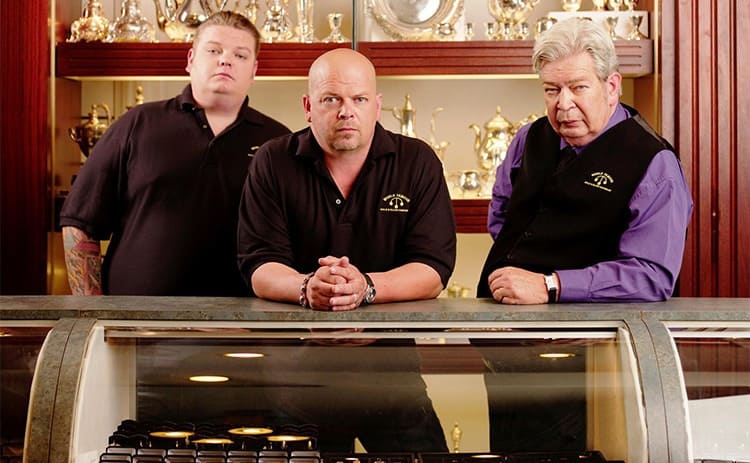 Corey, Rick, and Richard Harrison in front of a glass display of merchandise