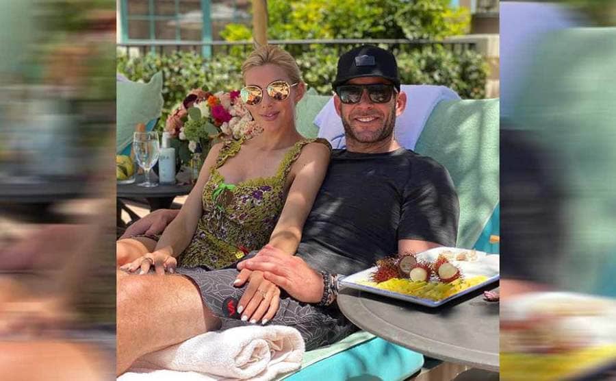 Heather and Tarek posing together on lounge chairs by the pool