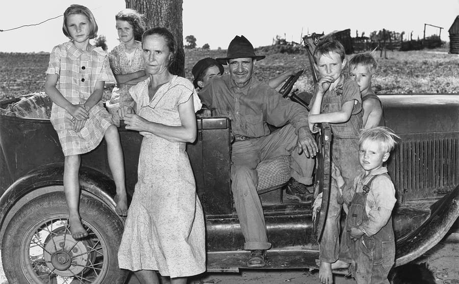 A family posing around a car in the 1930s