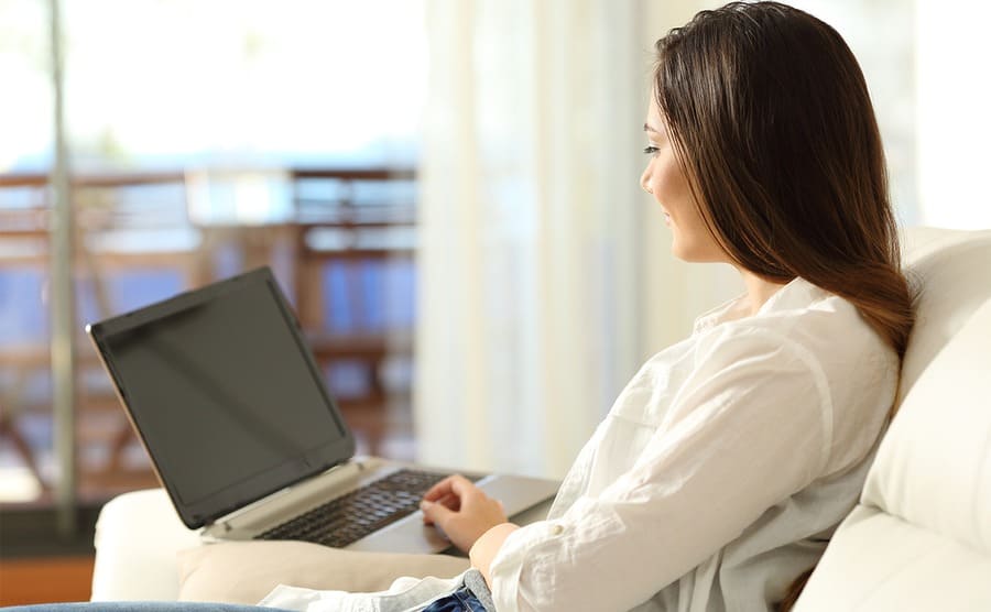 A woman on a laptop sitting on her couch