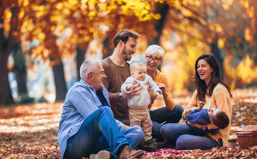 A happy family laughing while sitting in an autumn park